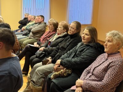 Cilvēku grupa sēž sanāksmē, uzmanīgi raugoties uz priekšu. Snēpelē iedzīvotāji un pašvaldība diskutē par pagasta attīstību